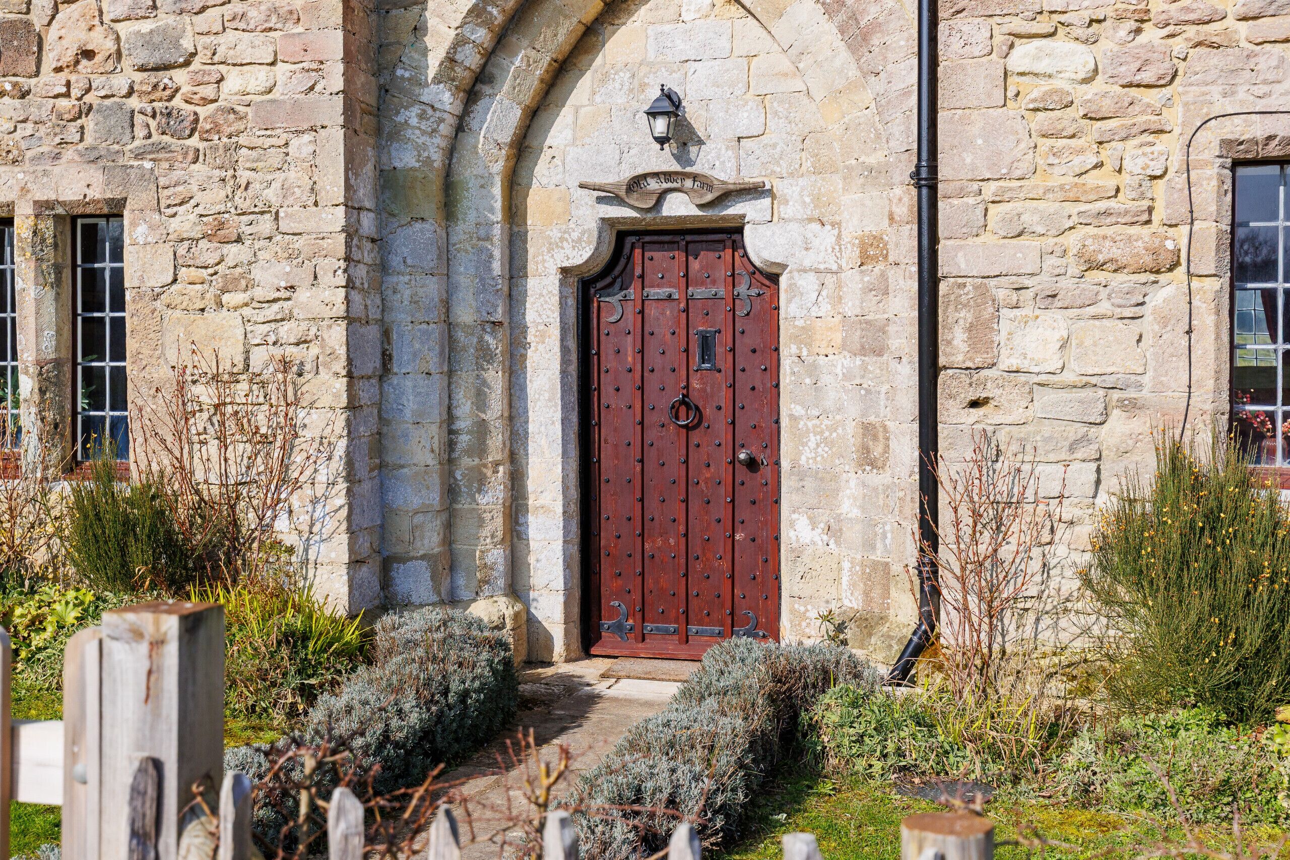 A stone building with a red door, a small window, and a sign above the door.