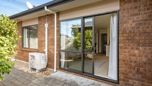 Et moderne hus med facade i mursten, store skydedøre der fører til en opholdsstue, og en aircondition på jorden.