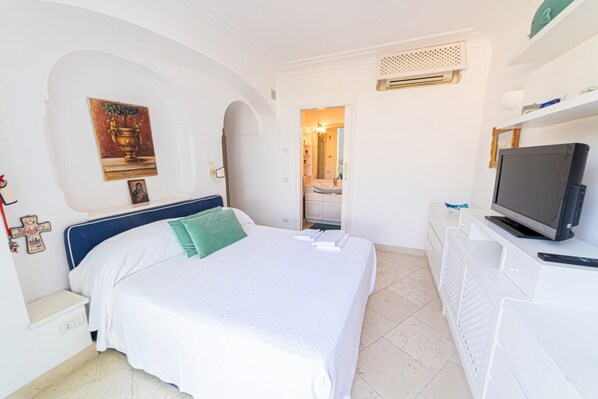 Une chambre d’hôtel avec un lit, une télévision et une salle de bain que l’on aperçoit à travers une arche.