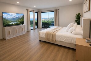 A bedroom with a large bed, a TV, and a view of mountains and a lake.
