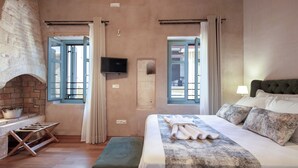A bedroom with a bed, a TV, and a brick wall. - DOMUS CLODIA, sensing Rethymno's Old Town! (Rethymno)