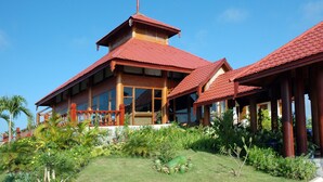 A large, two-story building with a red-tiled roof, large windows, and a covered outdoor area with wooden pillars. - One Myanmar Resort Nay Pyi Taw (Naypyidaw)
