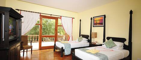 A room with two beds, a wooden cabinet, a chair, and a large window with curtains.