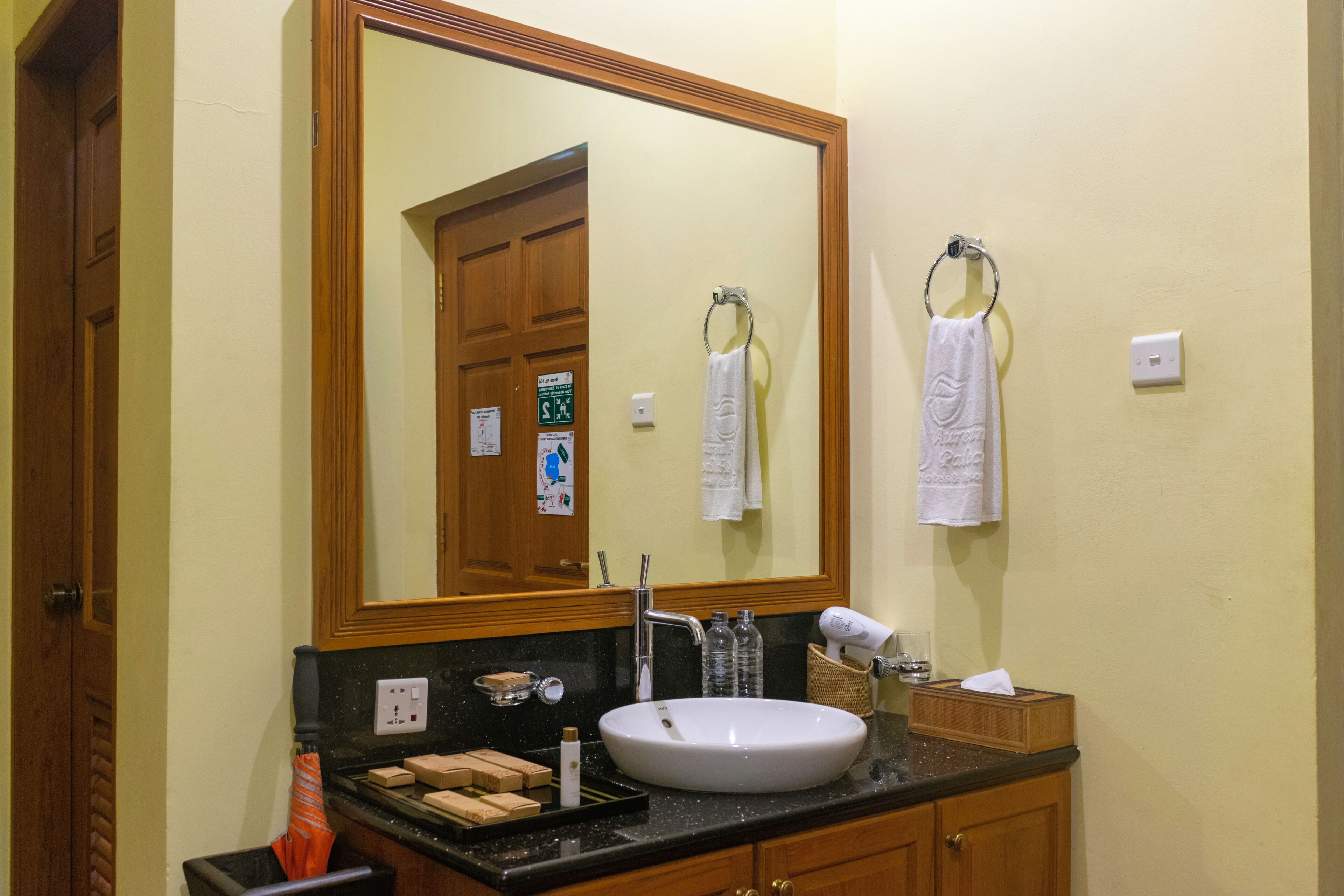 A bathroom with a large mirror, a sink, a towel rack, and a wooden cabinet.