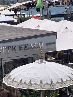 Un restaurant situé en bord de mer, appelé « COTTETTE BEACH », avec une terrasse et des parasols.
