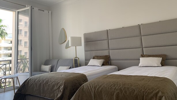 Habitació d'hotel moderna amb dos llits, una finestra gran i un balcó.