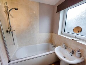 A bathroom with a bathtub, a sink, and a window with a view. - 2 Spring Gardens - 2 bed holiday bungalow (Cayton)