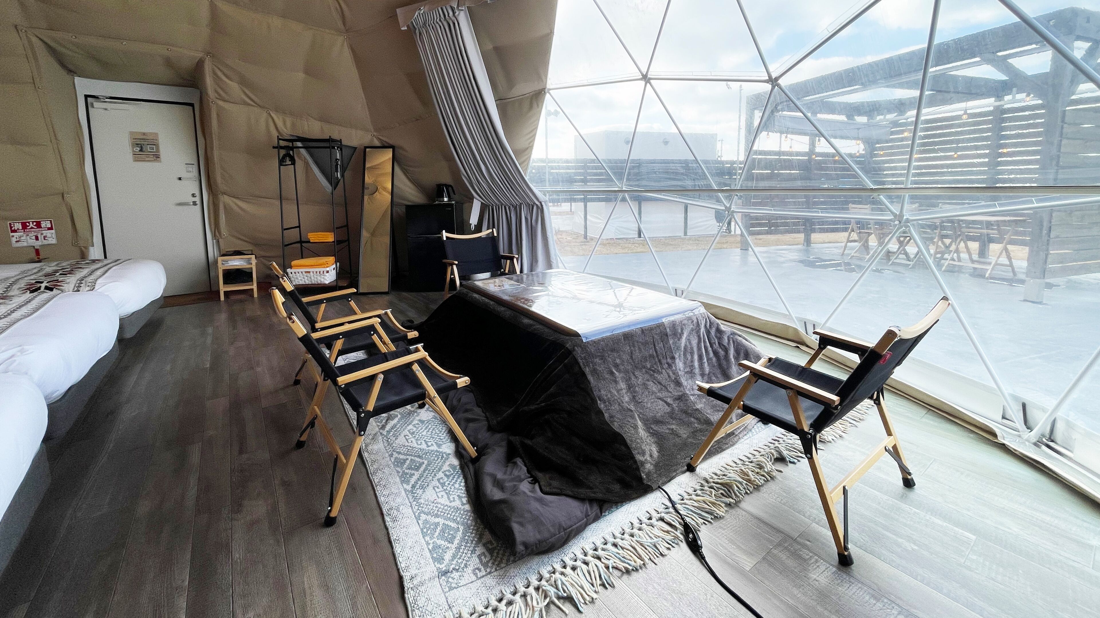 A room with a large window, a bed, a desk, and a chair.