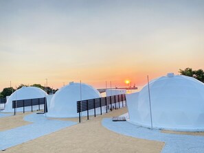 A row of dome-shaped structures with a paved walkway leading to them, set against a sunset backdrop. - EIGHT POINT RESORT AWAJISHIMA - Glamping (Awaji)