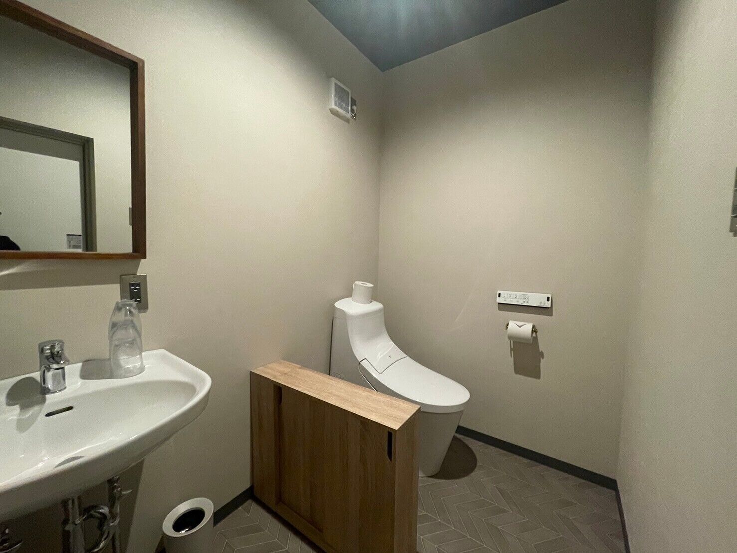 A compact bathroom with a sink, mirror, toilet, and a small cabinet.
