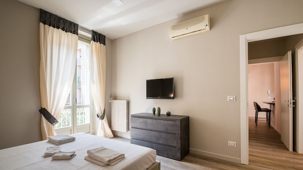 Une chambre à coucher comprenant un lit, une commode, un téléviseur à écran plat et un appareil de climatisation.