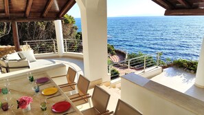 Un espace extérieur lumineux, aménagé pour les repas, avec vue sur la mer, et comprenant une table, des chaises et un canapé.