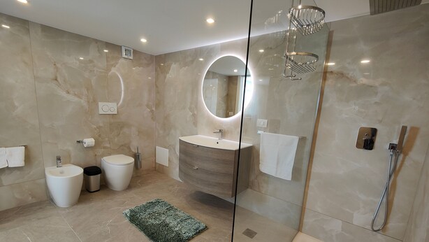 Une salle de bain moderne avec une douche à parois de verre, un meuble-lavabo avec un miroir et des toilettes.