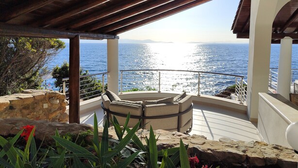 A covered outdoor seating area with a view of the sea.