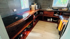 Una cocina moderna con encimera de madera, estantes empotrados, microondas y ventana que proporciona luz natural.