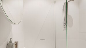 Ein modernes Badezimmer mit Duschkabine aus Glas, weißer Toilette und Waschtisch mit Spiegel.
