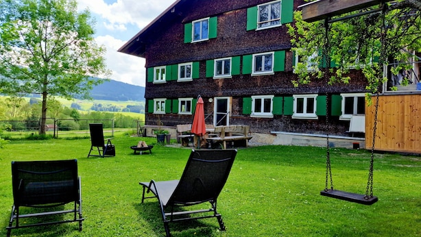 A rustic chalet with a wooden deck, outdoor seating, and a swing. - Quaint farmhouse in the countryside with its own garden, 10 beds (Weitnau)