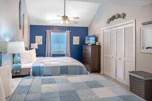 A bedroom with two beds, a ceiling fan, a television, a dresser, a closet, and a window with curtains.