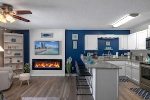 Una cocina moderna con chimenea, zona de bar y armarios blancos.