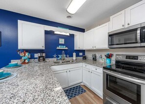 A kitchen with white cabinets, a microwave, an oven, and a coffee maker.