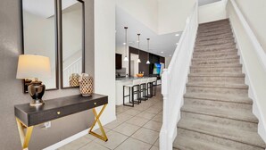 Une cuisine moderne dotée d’un îlot central, d’un coin repas avec des tabourets de bar et d’un escalier menant à un niveau supérieur.