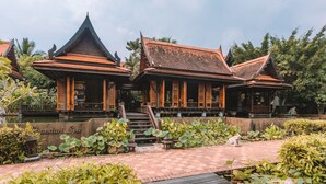 A traditional building with a tiled roof and wooden structures, surrounded by a garden with lotus plants and a pond. - Khaolak Oriental Resort - Adult Only (Takua Pa)