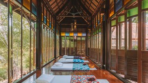 A corridor with multiple beds aligned along the walls, large windows, and a wooden ceiling. - Khaolak Oriental Resort - Adult Only (Takua Pa)