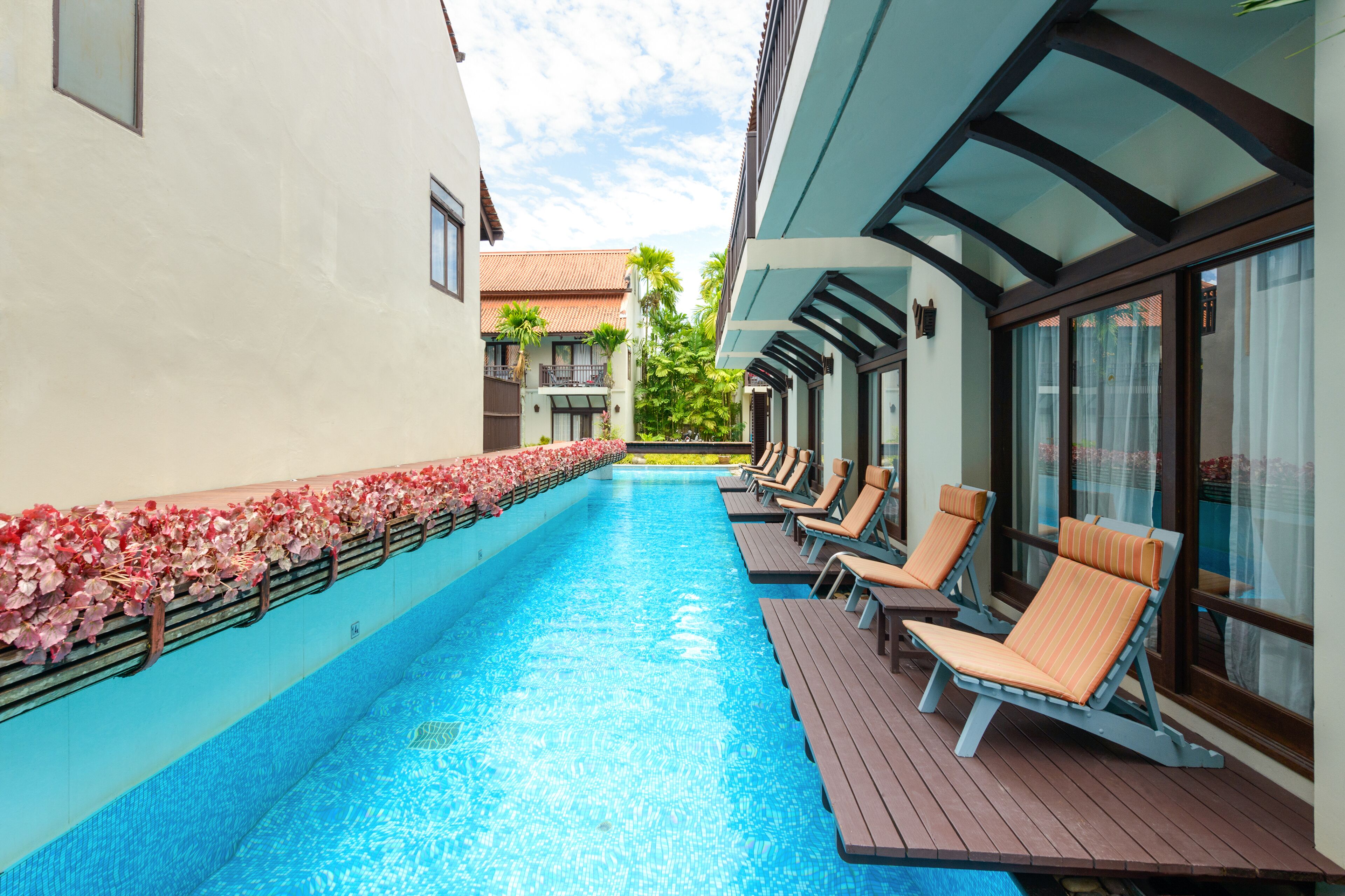 Piscina con sillones de descanso y una capa de flores.