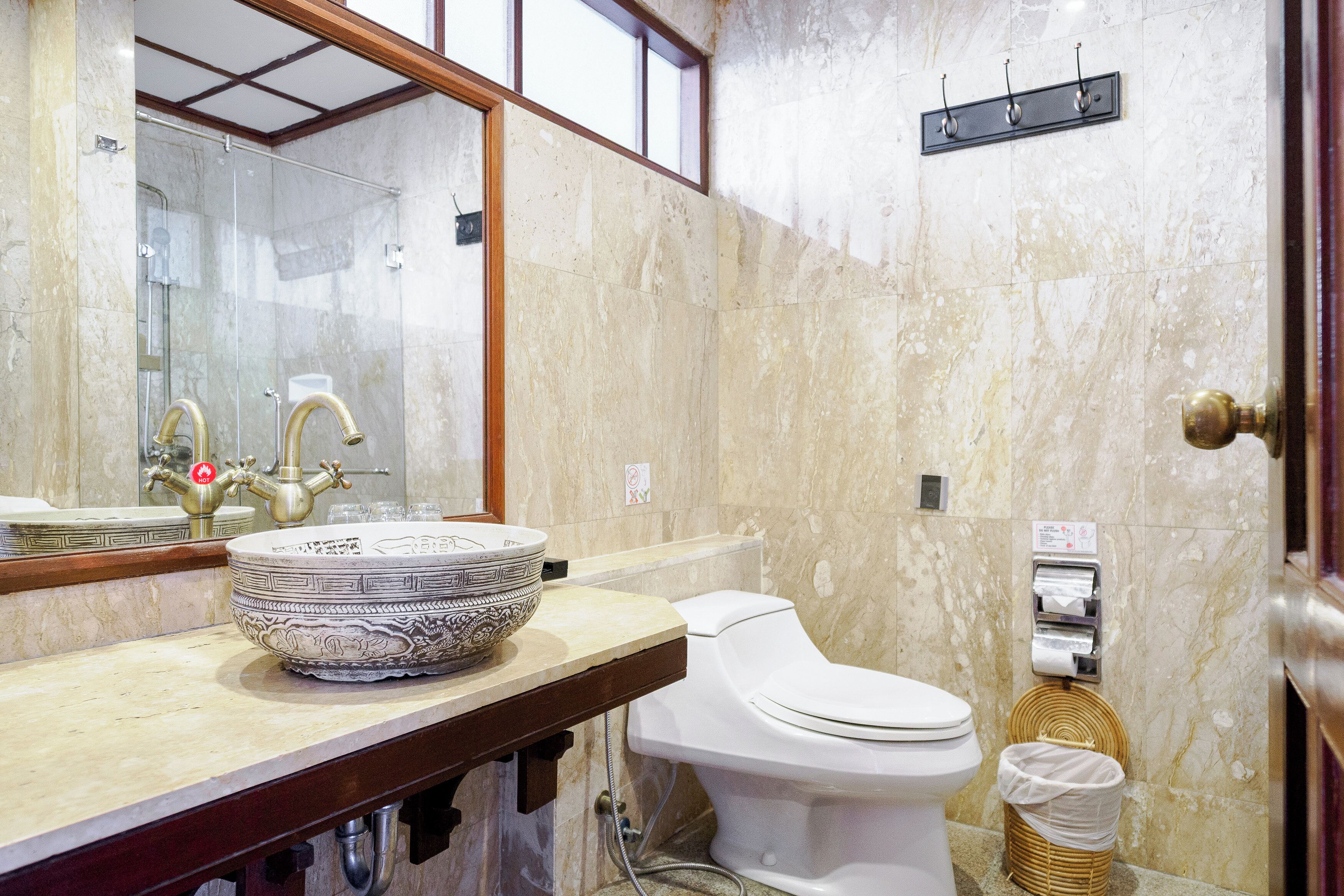 A bathroom with a marble sink, a toilet, and a glass-enclosed shower.