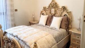 A bed with an ornate headboard, a bedside table with a lamp, and a dresser with drawers. - Vesime Villa with Garden (Vesime (AT))