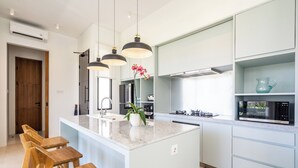 Eine moderne Küche mit einer zentralen Kochinsel, Pendelleuchten und Holzstühlen.