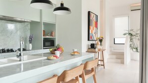 Eine moderne Küche mit Marmorarbeitsplatte, Holzstühlen und Pendelleuchten.