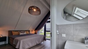 A bedroom with a bed, bedside table, and a large window. - Water Villa in Balk by Frisian Lakes (Balk)