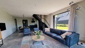 A modern living room with a sofa, coffee table, and staircase. - Water Villa in Balk with Lake Access (Balk)