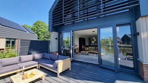 Ein modernes Haus mit Terrasse, einer Couch und einem Esstisch.