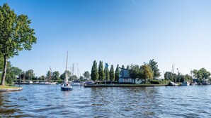 A calm water body with boats, trees, and a building with a blue roof. - Waterfront Villa w/ Jetty (Balk)