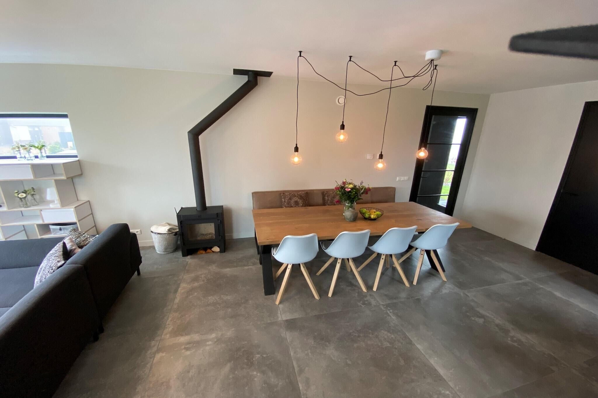 Un espace repas moderne avec une table en bois, quatre chaises et des luminaires suspendus.