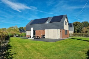 A modern house with solar panels, a covered patio, and a well-maintained lawn. - Waterfront Villa w/ Jetty (Balk)