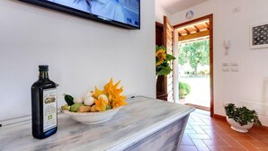 A reception area with a marble counter, a bottle of olive oil, and a bowl of fruit. A television is mounted on the wall, and a door leads outside. - Casa de' Fossi (Reggello)