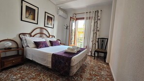 Une chambre à coucher avec un lit, une table de chevet, une chaise et une fenêtre avec des rideaux.