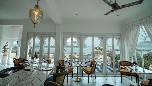 A dining area with a view of the sea, featuring a chandelier, ceiling fan, and checkered floor. - Burj Baneria - A Boutique Homestay (Udaipur)