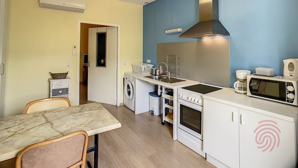 Een kleine keuken met een wasmachine, magnetron en fornuis.