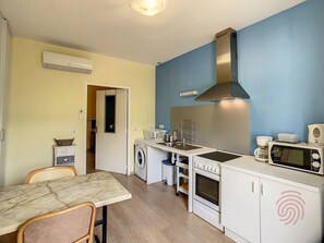 A compact kitchen with a washing machine, microwave, and stove.