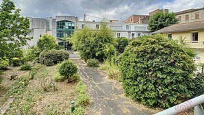Een patio met een verhard pad, omringd door groen en gebouwen met moderne architectuur.