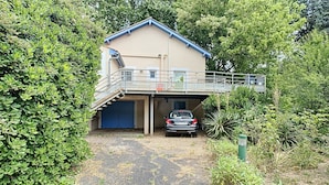 Een twee verdiepingen tellend huis met een garage, een overdekte oprit en een balkon.