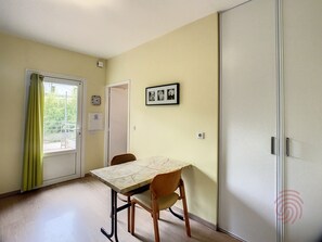 Een kamer met een eettafel en stoelen, een deur en een raam met gordijnen.