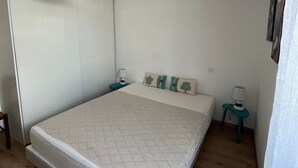 Une chambre à coucher avec un lit, deux tables de chevet, une lampe suspendue et un tableau accroché au mur.