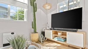 Una sala moderna con un televisor de pantalla plana grande, un cactus y una planta en maceta.