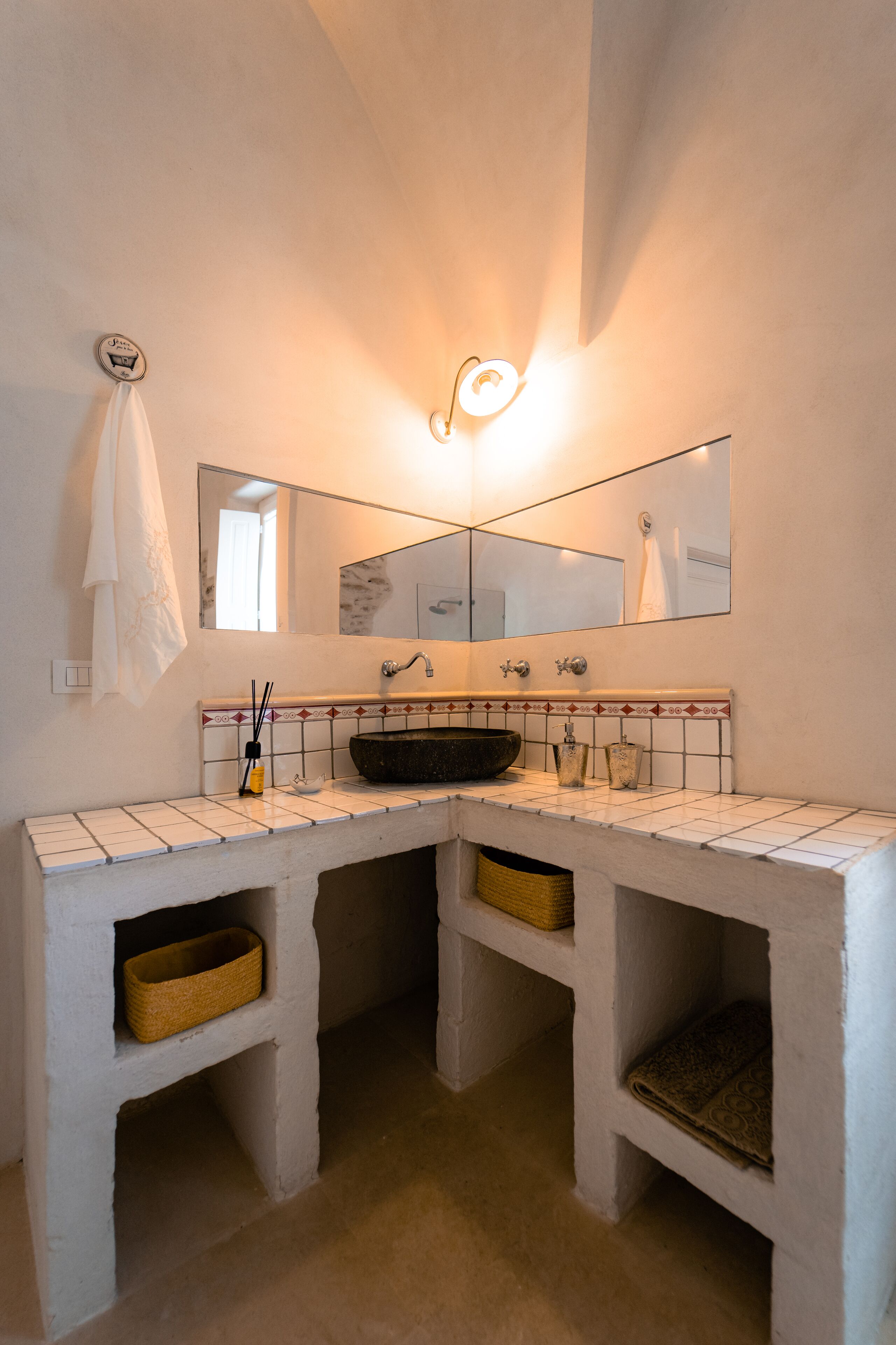 Une salle de bain avec un meuble-lavabo aux carreaux blancs, un lavabo sur pied noir, un miroir au-dessus du lavabo et une serviette accrochée au mur.