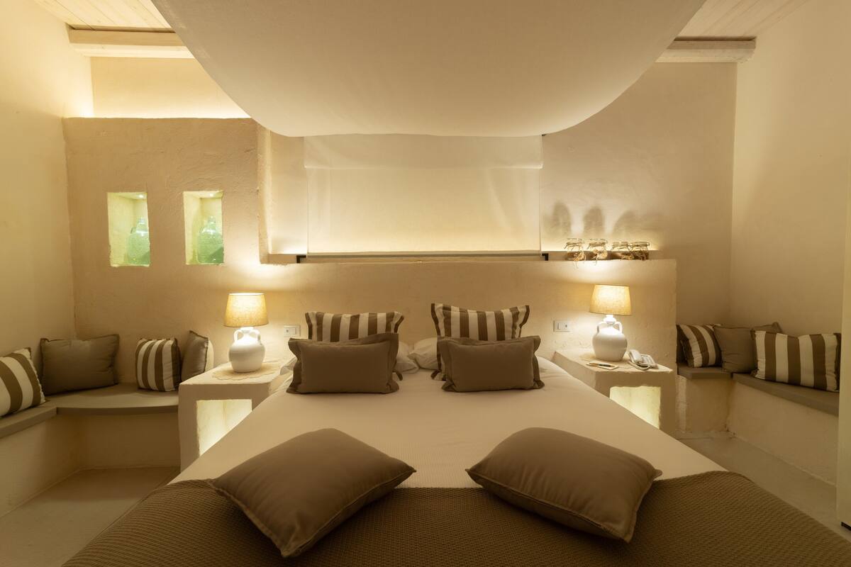 Une chambre spacieuse avec un grand lit, deux tables de chevet avec des lampes et une fenêtre donnant sur un beau paysage.